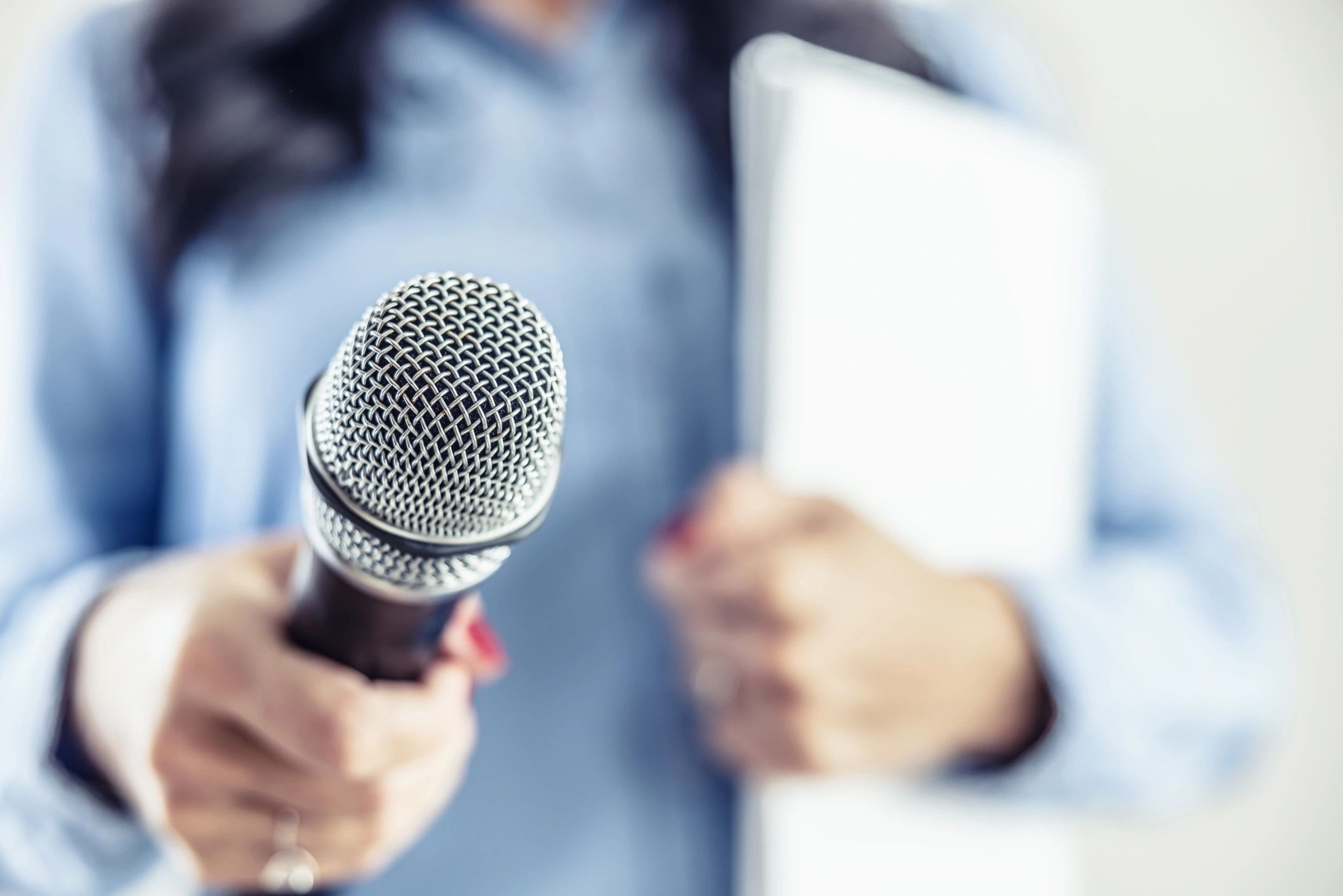 Investigative journalist with microphone in other hand notebook
